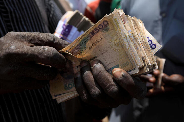 FILE PHOTO: A man carries Nigerian naira banknotes at a livestock market in Abuja, Nigeria July 29, 2020. REUTERS/Afolabi Sotunde/File Photo