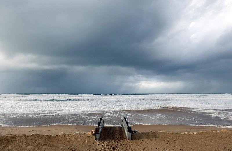 Clouds hang in the sky above the Atlantic ocean as waves from an early winter storm covers the beachfront in Lacanau
