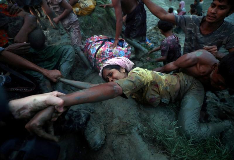 Photographers help a Rohingya refugee to come out of Naf River as they cross the Myanmar-Bangladesh border in Palong Khali, near Cox's Bazar, Bangladesh, November 1, 2017. Hannah McKay