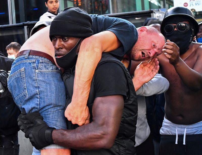 Protester Patrick Hutchinson carries an injured counter-protester to safety, near the Waterloo station during a Black Lives Matter protest following the death of George Floyd in Minneapolis police custody, in London, Britain, June 13, 2020. Picture taken June 13, 2020. REUTERS/Dylan Martinez