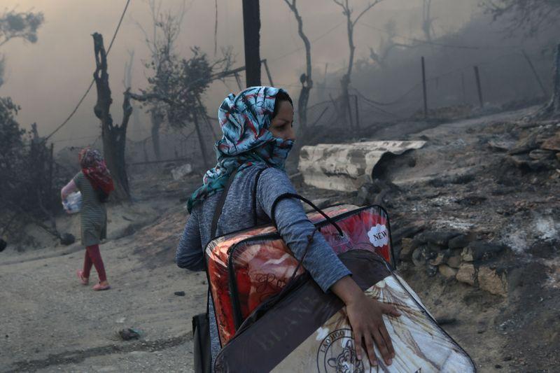 A migrant carries her belongings following a fire at the Moria camp for refugees and migrants on the island of Lesbos, Greece, September 9, 2020. REUTERS/Elias Marcou