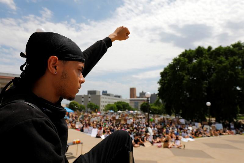 A protester raises his fist during a peaceful demonstration near the Minnesota State Capitol after a white police officer was caught on a bystander's video pressing his knee into the neck of African-American man George Floyd, who later died at a hospital, in St. Paul, Minnesota, U.S. June 2, 2020. REUTERS/Adam Bettcher