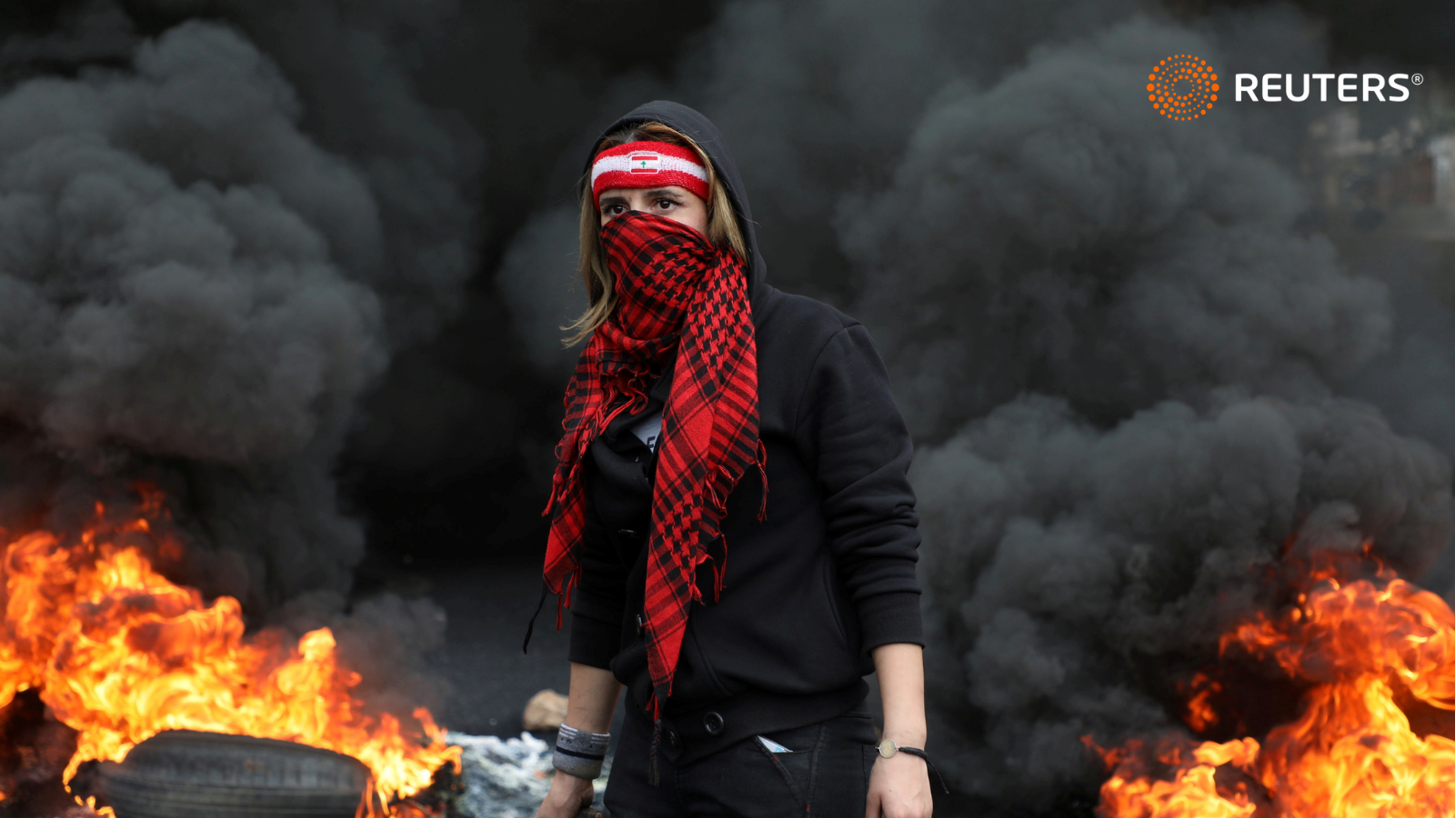 A demonstrator stands near a burning fire during a protest in Zouk