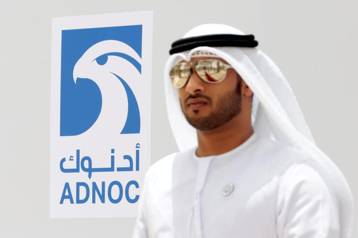 FILE PHOTO: An Emirati man is seen near the logo of  ADNOC in Ruwais, United Arab Emirates May 14, 2018. Picture taken May 14, 2018. REUTERS/Christopher Pike/File Photo