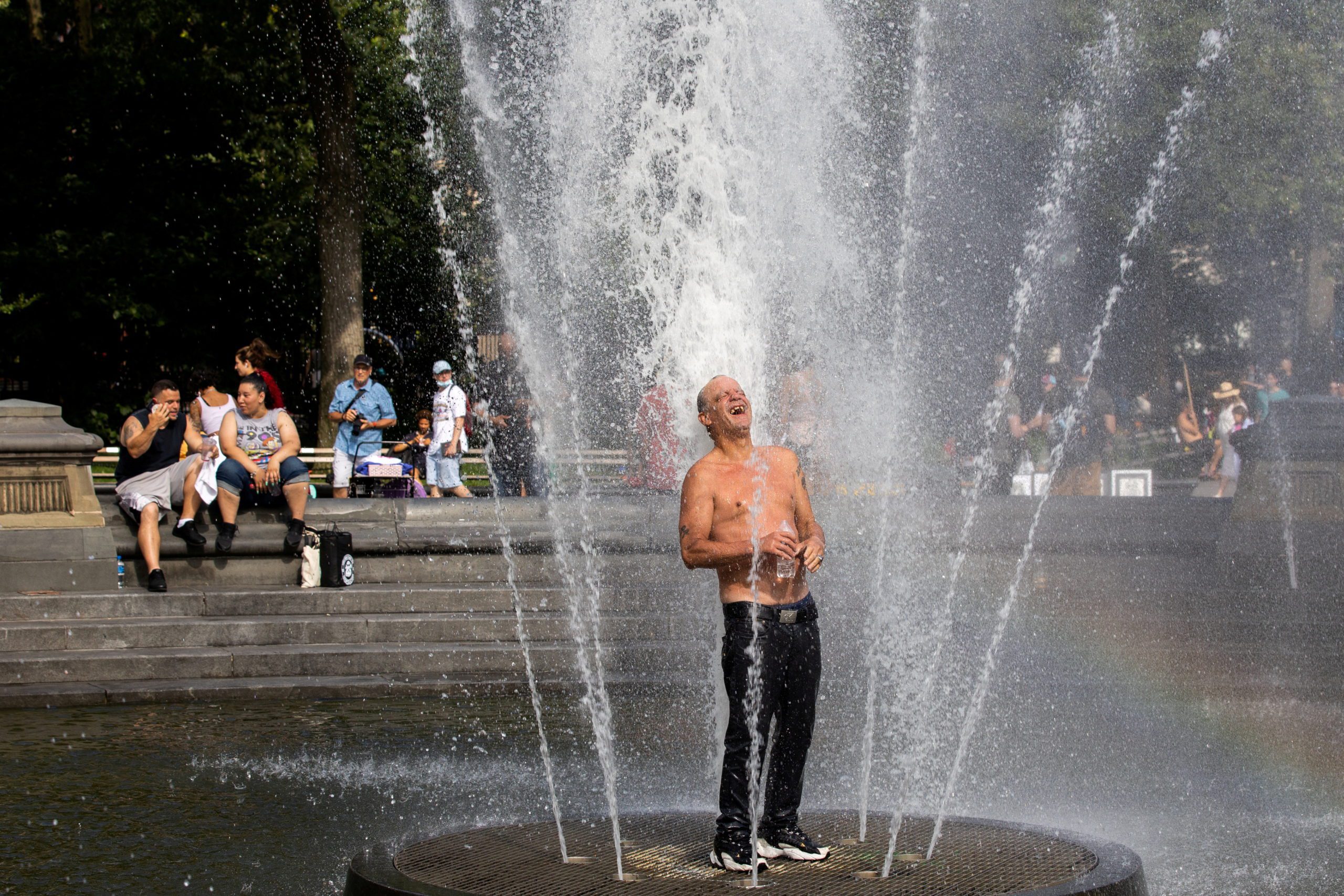 A man cools off himself on a fountain during a heat wave in New York City