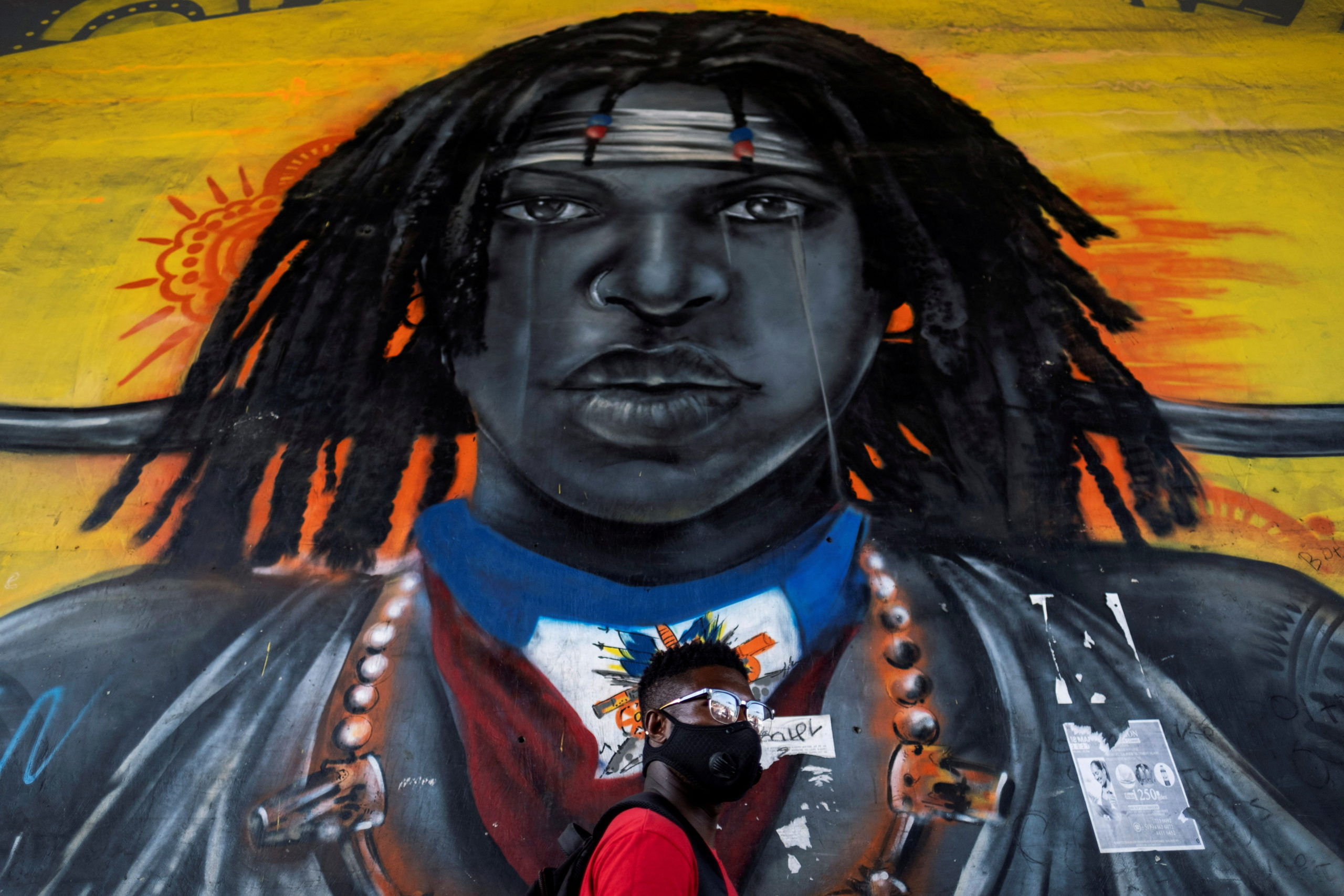 A man walks past a mural under an overpass in Port-au-Prince