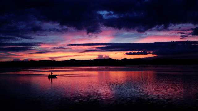 A man fishes on a boat at Lake Hamana in the sun set in Hamamatsu