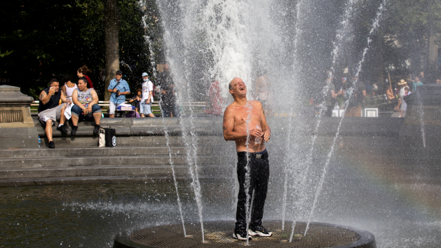 A man cools off himself on a fountain during a heat wave in New York City