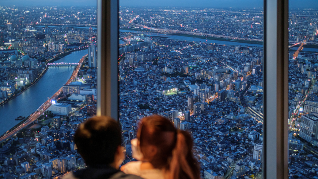 A couple watches office and residential buildings from the observation deck of Tokyo Skytree