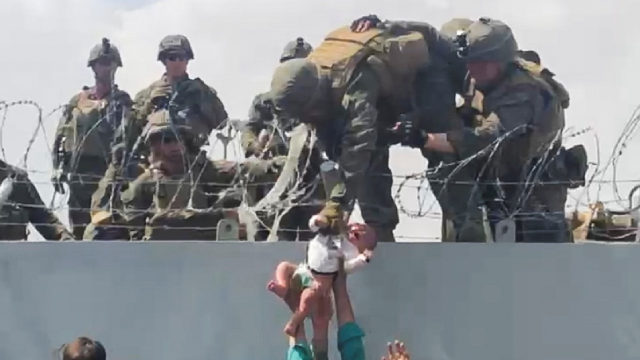 A baby is handed over to the American army over the perimeter wall of the airport in Kabul