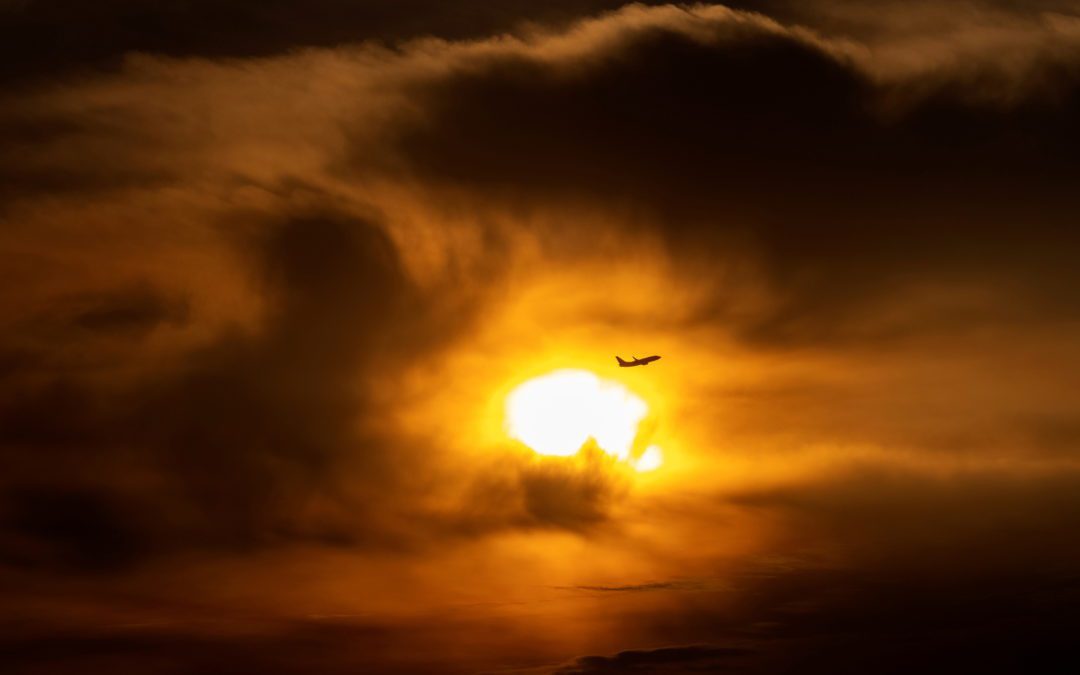 A commercial airliner takes off through clouds during sunrise, near Huntington Beach, California