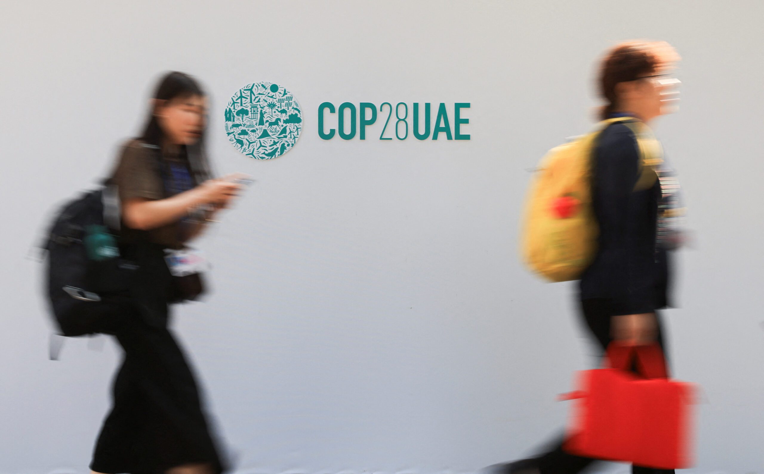 Delegates walk past a logo of the COP28 climate summit in Dubai, United Arab Emirates, December10, 2023. REUTERS/Thaier Al Sudani