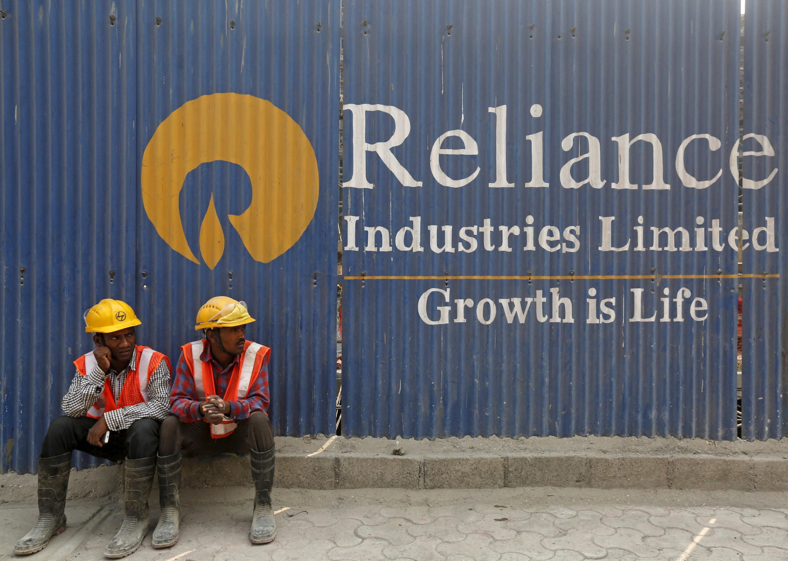 FILE PHOTO: Labourers rest in front of an advertisement for Reliance Industries Limited at a construction site in Mumbai, India, March 2, 2016. REUTERS/Shailesh Andrade/File Photo