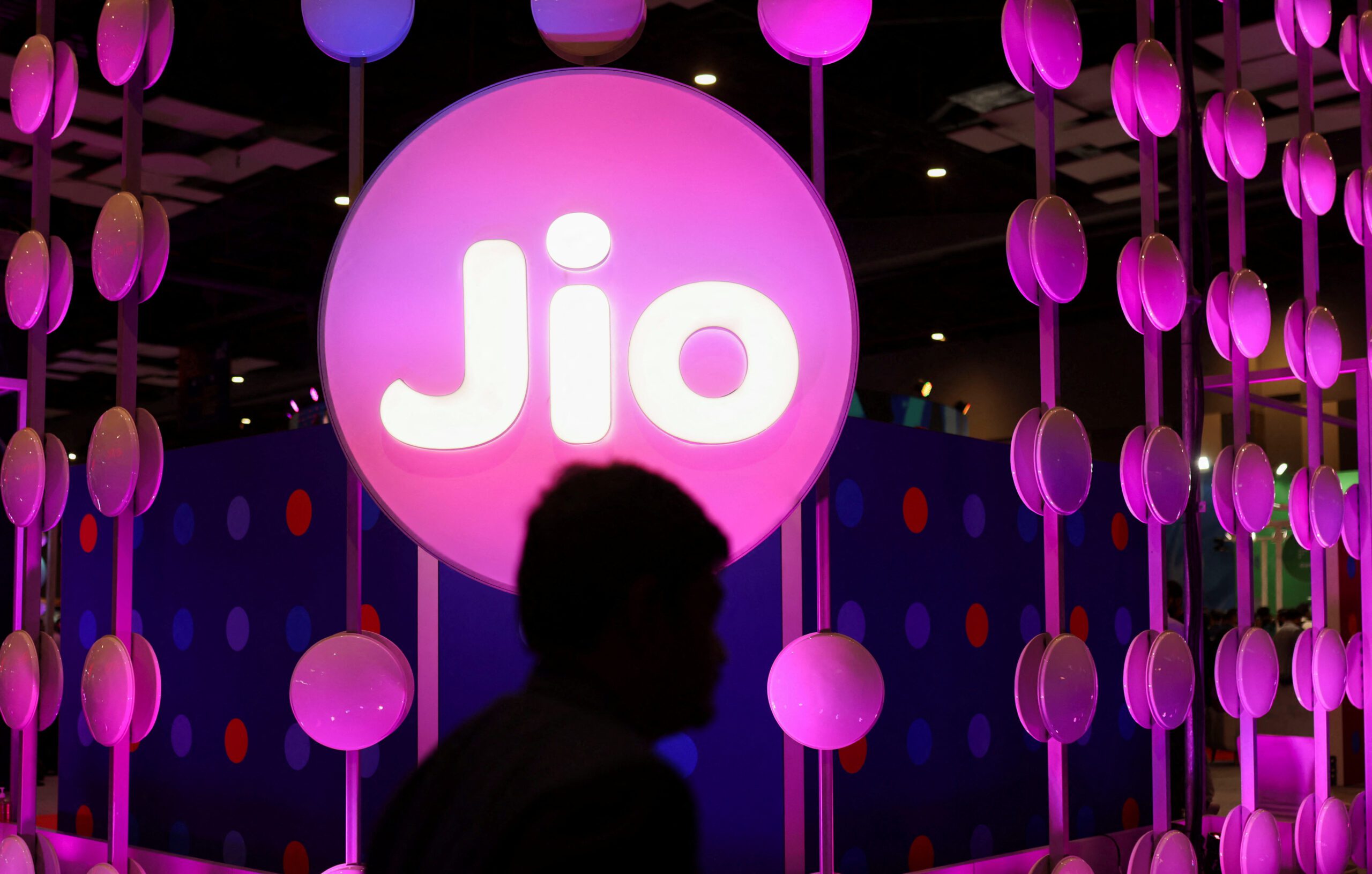 FILE PPHOTO: A man walks across the LED board showing the logo of Jio at the ongoing India Mobile Congress 2022, at Pragati Maidan, in New Delhi, India, October 3, 2022. REUTERS/Anushree Fadnavis/File Photo